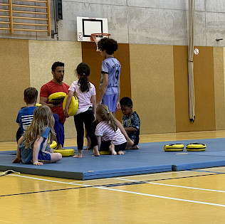 Kickbox-Trainer bespricht mit seiner Gruppe auf einem Mattenkreis die nächste Übung